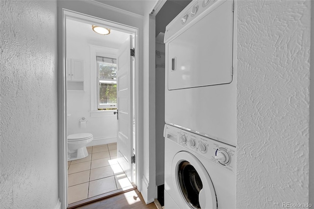 laundry area with stacked washer / drying machine and tile patterned floors