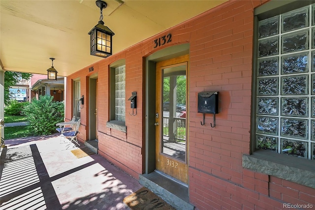 property entrance with a porch and brick siding