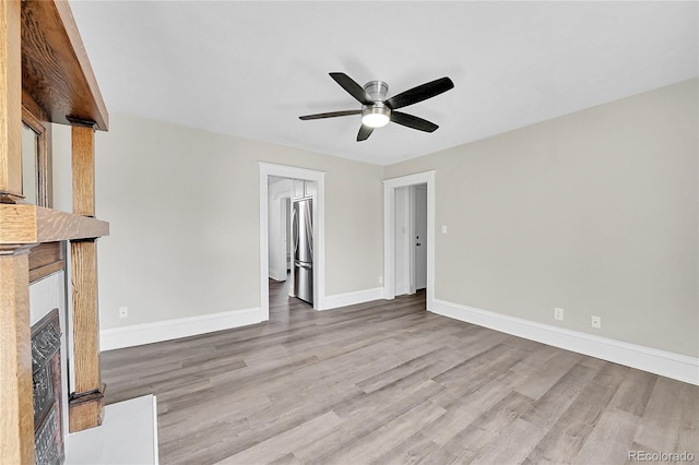 unfurnished living room with a fireplace with flush hearth, baseboards, ceiling fan, and light wood finished floors