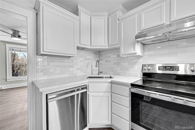 kitchen featuring under cabinet range hood, a sink, light countertops, appliances with stainless steel finishes, and decorative backsplash