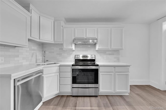 kitchen with stainless steel appliances, light countertops, a sink, and under cabinet range hood