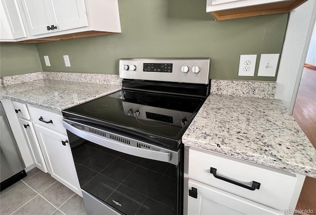 kitchen featuring white cabinets, light tile patterned floors, stainless steel electric range, and light stone countertops