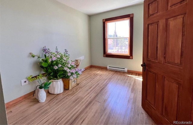 interior space with a baseboard heating unit and light hardwood / wood-style floors