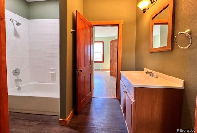 bathroom with a baseboard heating unit, tiled shower / bath combo, hardwood / wood-style flooring, and vanity