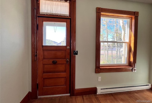 foyer with a baseboard heating unit, a healthy amount of sunlight, and hardwood / wood-style floors