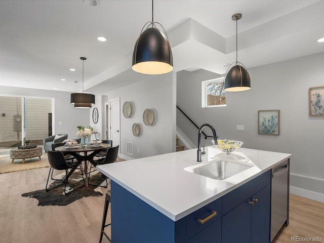 kitchen with blue cabinets, dishwasher, sink, and a center island with sink