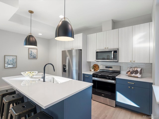 kitchen with blue cabinets, a center island with sink, and appliances with stainless steel finishes