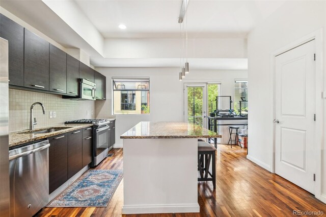 2325 Walnut St Unit 4, Denver, CO 80205 - kitchen featuring appliances with stainless steel finishes, a sink, a center island, a kitchen breakfast bar, and wood finished floors