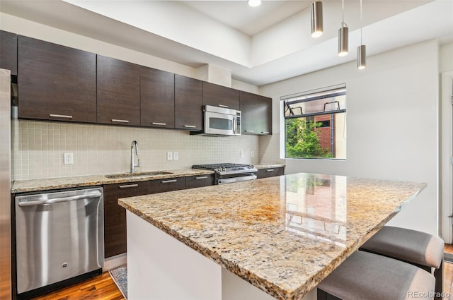 2325 Walnut St Unit 4, Denver, CO 80205 - kitchen featuring appliances with stainless steel finishes, a sink, wood finished floors, a center island, and dark brown cabinets
