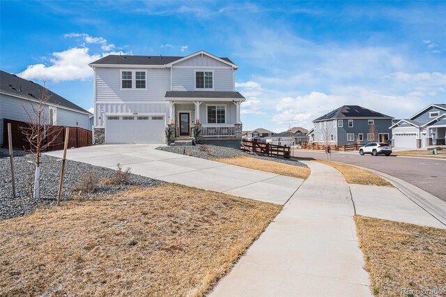 traditional home with driveway, stone siding, a porch, board and batten siding, and an attached garage