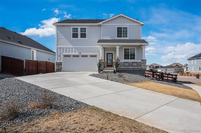 view of front of property featuring driveway, stone siding, covered porch, board and batten siding, and a garage