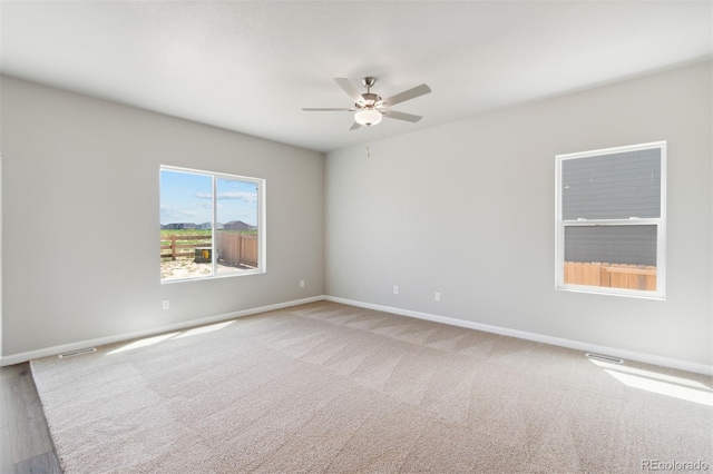 empty room featuring a ceiling fan, visible vents, carpet floors, and baseboards