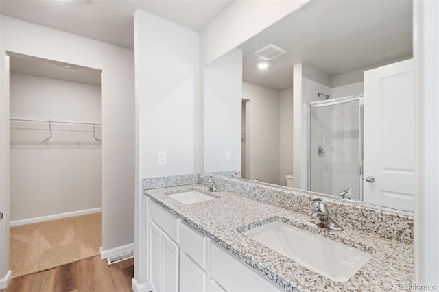 bathroom with a shower stall, toilet, visible vents, and a sink