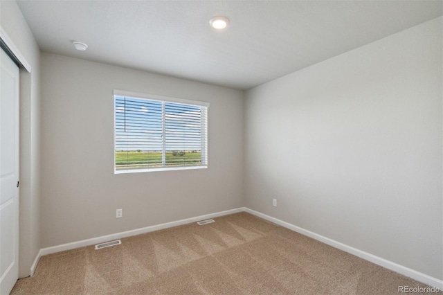 unfurnished room featuring light colored carpet, visible vents, and baseboards