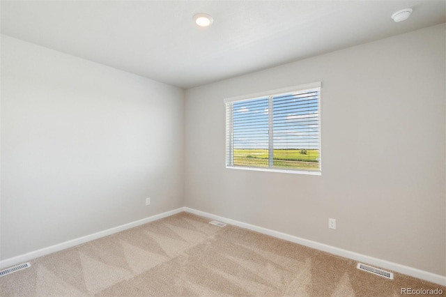 spare room with visible vents, light colored carpet, and baseboards