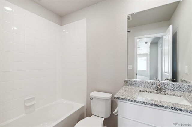 full bath with tub / shower combination, toilet, vanity, and a textured wall