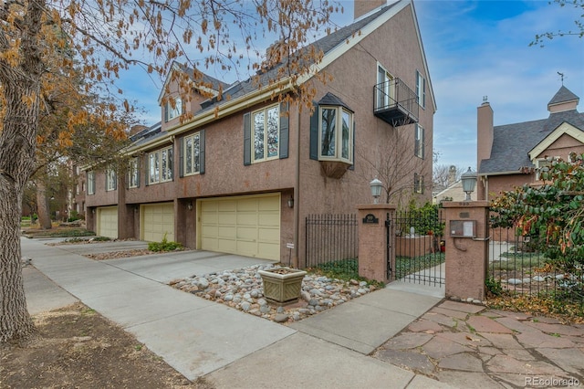 view of home's exterior with a chimney, concrete driveway, fence private yard, an attached garage, and stucco siding