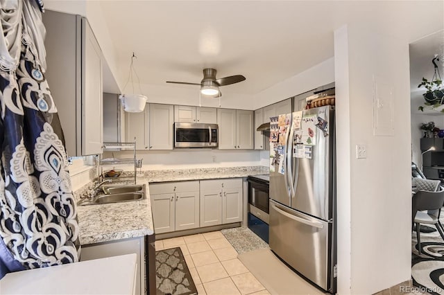 kitchen with light tile patterned floors, ceiling fan, gray cabinetry, stainless steel appliances, and a sink