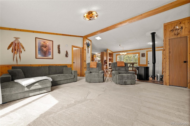 carpeted living room with vaulted ceiling with beams, ornamental molding, a wood stove, an inviting chandelier, and a textured ceiling