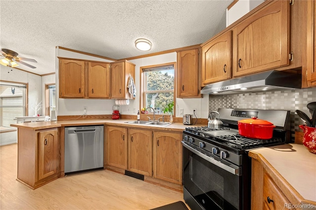 kitchen featuring a sink, stainless steel appliances, light countertops, light wood-style floors, and under cabinet range hood