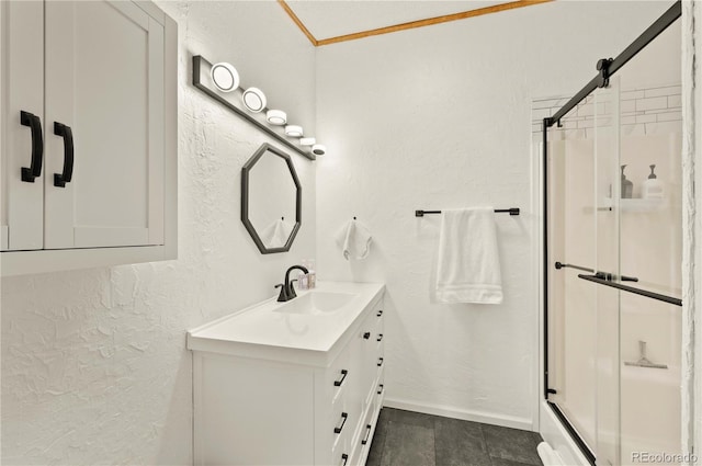 bathroom with vanity, baseboards, ornamental molding, a shower stall, and a textured wall