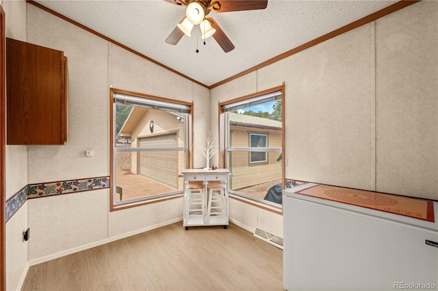 interior space with ornamental molding, a textured ceiling, wood finished floors, lofted ceiling, and ceiling fan