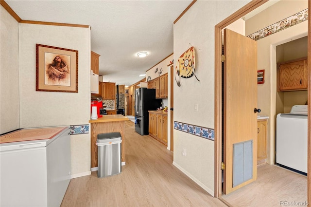 hallway featuring visible vents, a textured ceiling, washer / dryer, and light wood-style flooring