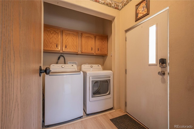 laundry room with cabinet space, separate washer and dryer, and light wood-type flooring