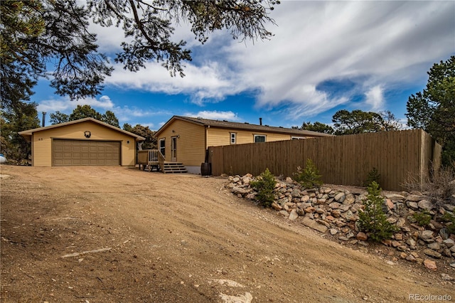 view of side of home with a detached garage, fence, and an outbuilding