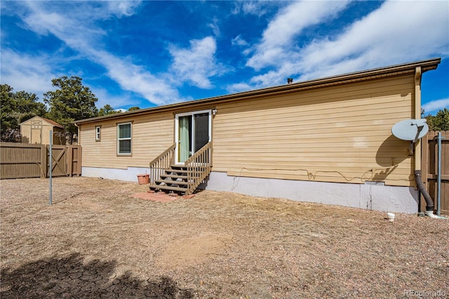 rear view of property with entry steps, a gate, and fence