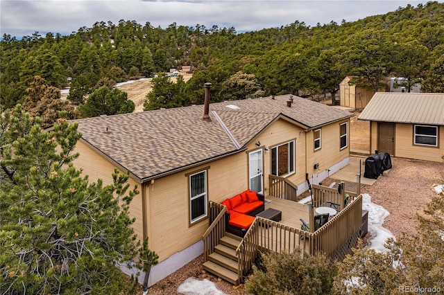 back of property with a deck and roof with shingles