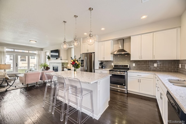 15576 W Washburn Cir, Lakewood, CO 80228 - kitchen featuring wall chimney exhaust hood, stainless steel appliances, a center island, dark wood finished floors, and open floor plan