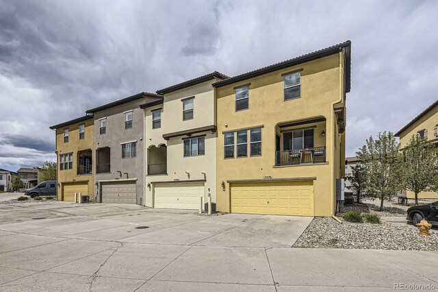 15576 W Washburn Cir, Lakewood, CO 80228 - view of front of home with a garage, driveway, stucco siding, and central air condition unit