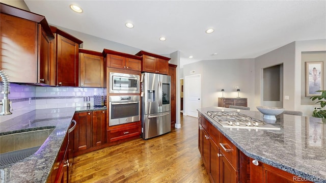 6945 N Fargo Trl, Littleton, CO 80125 - kitchen featuring appliances with stainless steel finishes, light wood finished floors, a sink, backsplash, and dark stone countertops