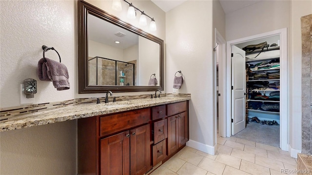 6945 N Fargo Trl, Littleton, CO 80125 - full bathroom with a stall shower, tile patterned floors, a walk in closet, double vanity, and baseboards