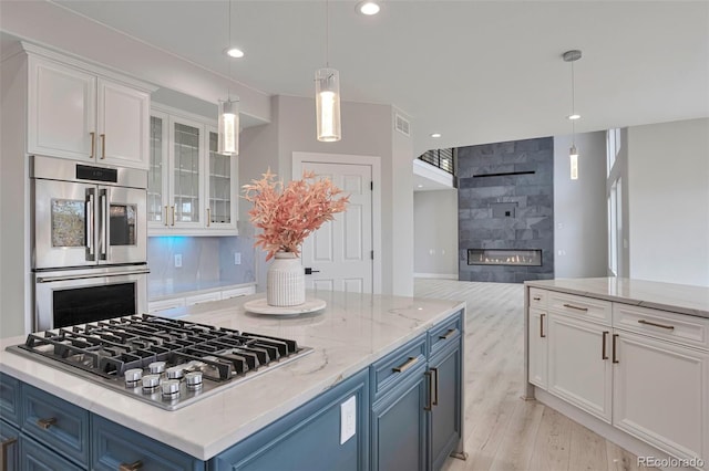 kitchen with blue cabinetry, white cabinetry, appliances with stainless steel finishes, and light hardwood / wood-style floors