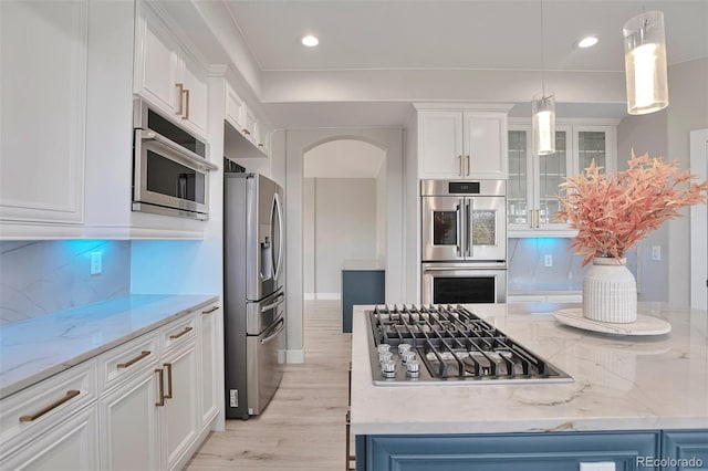 kitchen with decorative backsplash, white cabinetry, light hardwood / wood-style floors, decorative light fixtures, and stainless steel appliances