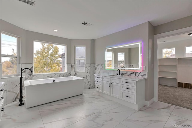 bathroom with vanity, tile walls, a healthy amount of sunlight, and a bath