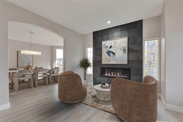 living area with a chandelier, a fireplace, and light wood-type flooring