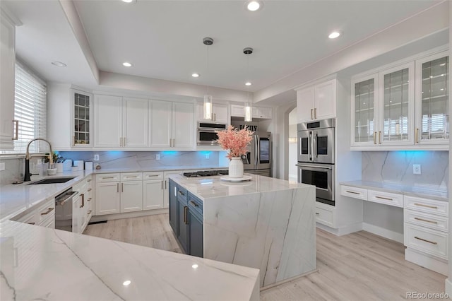 kitchen featuring light stone countertops, a center island, white cabinets, and pendant lighting