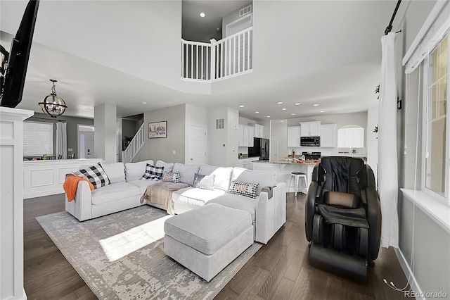 living room featuring a healthy amount of sunlight, dark wood-type flooring, and a chandelier