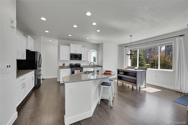 kitchen with white cabinetry, sink, stainless steel range with gas cooktop, pendant lighting, and a kitchen island with sink