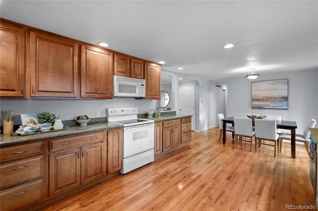 6243 S Elati St, Littleton, CO 80120 - kitchen featuring white appliances, brown cabinetry, arched walkways, recessed lighting, and dark countertops