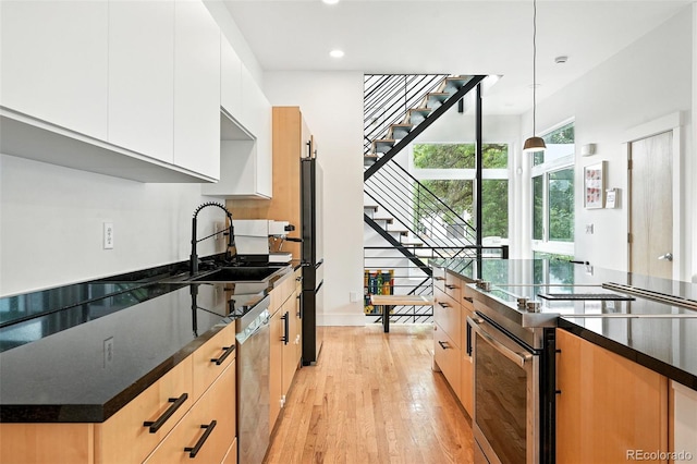 4129 Zenobia St, Denver, CO 80212 - kitchen featuring stainless steel appliances, light wood finished floors, recessed lighting, hanging light fixtures, and white cabinets
