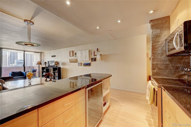 kitchen featuring electric stove, tasteful backsplash, light brown cabinets, beverage cooler, and light wood-type flooring