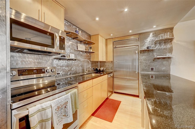 kitchen featuring light brown cabinetry, light hardwood / wood-style flooring, tasteful backsplash, appliances with stainless steel finishes, and sink