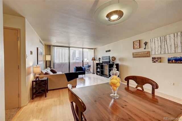 dining space featuring floor to ceiling windows, a textured ceiling, and light hardwood / wood-style flooring