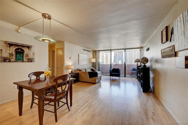 dining space featuring floor to ceiling windows, a textured ceiling, and light hardwood / wood-style flooring