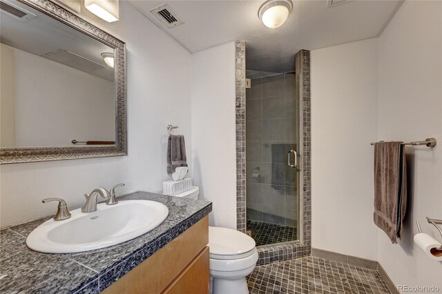 bathroom with tile patterned flooring, vanity, toilet, and walk in shower