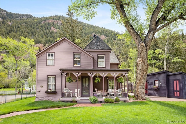 715 Main St, Georgetown, CO 80444 - victorian home featuring a porch, a chimney, a wooded view, and a mountain view